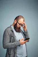 homem pensativo com barba com um telefone na mão, a solução para os problemas da vida. foto