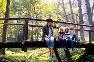 família feliz curtindo um dia na natureza e relaxando em uma ponte de madeira. foto