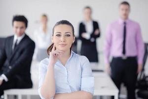 mulher de negócios em pé com sua equipe em segundo plano foto