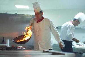 chef na cozinha do hotel preparar comida com fogo foto