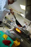 chef na cozinha do hotel preparar comida com fogo foto