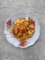 rujak buah ou salada de frutas indonésias na chapa branca, servida com molho picante de açúcar mascavo e amendoim moído. foto