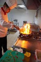 chef na cozinha do hotel preparar comida com fogo foto