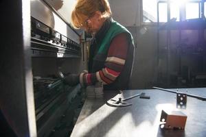 mulher trabalhando em uma fábrica moderna e preparando material para uma máquina cnc. foto