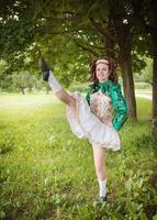 jovem menina bonita no vestido de dança irlandesa dançando ao ar livre