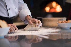 mãos de chef preparando massa para pizza foto