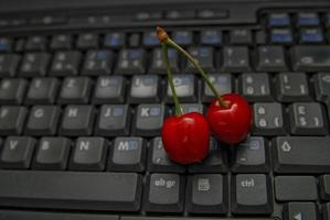 cereja fresca no teclado do laptop foto