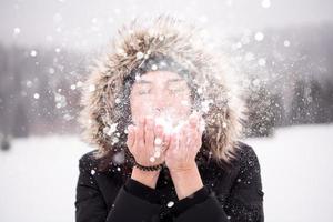 jovem soprando neve em dia de neve foto