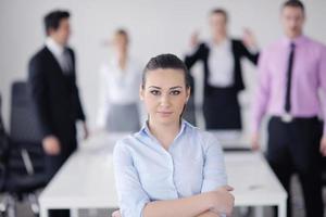 mulher de negócios em pé com sua equipe em segundo plano foto