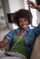 mulher afro-americana em casa na cadeira com telefones tablet e cabeça foto