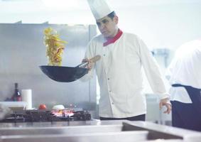 chef na cozinha do hotel preparar comida com fogo foto