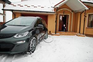 carregando o carro elétrico no quintal da casa no inverno. foto