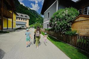 parte traseira da mãe com carrinho de bebê e crianças andando em hallstatt, salzkammergut, áustria. foto