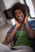 mulher afro-americana em casa na cadeira com telefones tablet e cabeça foto