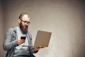 homem de estilo de vida bem sucedido com barba com laptop e telefone, plano de fundo, copyspace foto