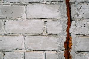 rachadura em uma velha parede de tijolos brancos, abstração de textura foto