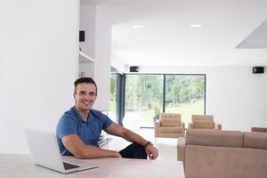 jovem com laptop em casa foto