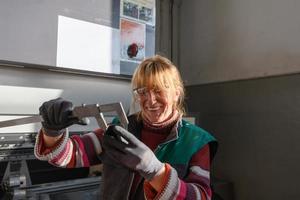 uma mulher que trabalha em uma moderna fábrica de produção e processamento de metais, preparando e medindo materiais que vão para o processamento de máquinas cnc foto