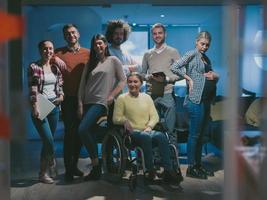 empresária com deficiência em cadeira de rodas no escritório com equipe de colegas de trabalho foto
