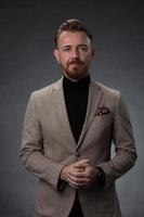 retrato de um elegante elegante empresário sênior com barba e roupas de negócios casuais em estúdio fotográfico isolado em fundo escuro, gesticulando com as mãos foto