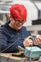 mulher trabalhador industrial soldando cabos de equipamentos de fabricação em uma fábrica foto