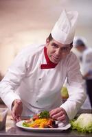 chef na cozinha do hotel preparando e decorando comida foto