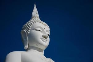 rosto da grande escultura de Buda branco no céu azul.