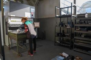 turquia, 2022 - mulher trabalhando em uma fábrica moderna e preparando material para uma máquina cnc. foto