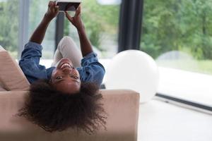 mulher afro-americana em casa com tablet digital foto