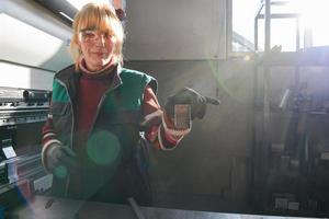 mulher trabalhando em uma fábrica moderna e preparando material para uma máquina cnc. foto