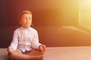 menino meditando com os olhos fechados. foto