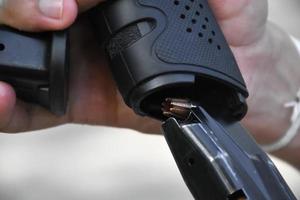 atirador está mudando o carregador de balas vazio com o novo carregador de balas completo na pistola, foco seletivo na bala no carregador. foto