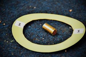cartuchos de bala de pistola e sinal de papel amarelo no chão, conceito para manter evidências físicas do uso de pistolas, armas e cartuchos de bala no ponto do assassinato. foto