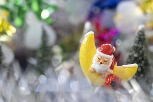 papai noel dorme na lua croissant na frente de árvores de natal esperando por um festival engraçado de natal e feliz ano novo para criar cartão de felicitações, felicidade e conceito engraçado. foto