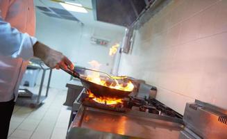 chef na cozinha do hotel preparar comida com fogo foto