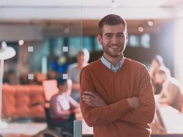 homem de negócios jovem bonito confiante no escritório na frente de sua equipe foto