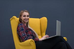 negócio de inicialização, mulher trabalhando no laptop e sentado na poltrona amarela foto