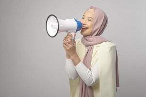 linda jovem segurando o megafone sobre estúdio de fundo branco. foto