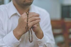 um fiel jovem asiático mãos em gesto de oração sentado sozinho no sofá na igreja orar e esperar boa sorte, sucesso, perdão. poder da religião, crença, deus fé foto