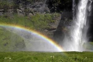 um arco-íris na frente da cachoeira seljalandsfoss na costa sul da islândia em um dia ensolarado foto