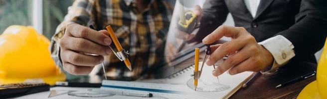 dois colegas discutindo dados de trabalho e tablet, laptop com projeto arquitetônico no canteiro de obras na mesa no escritório foto