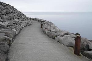 um caminho vazio que conduz em torno de uma curva na costa de keflavik, islândia foto