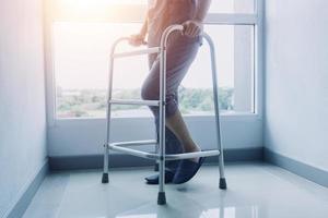 jovem fisioterapeuta asiático trabalhando com mulher sênior em andar com um andador foto