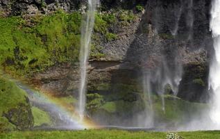 um arco-íris na frente da cachoeira seljalandsfoss na costa sul da islândia em um dia ensolarado foto