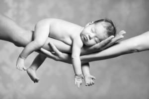 bebê dormindo nas mãos dos pais foto