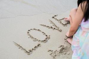 jovem feliz na praia escrevendo a palavra "amor" foto