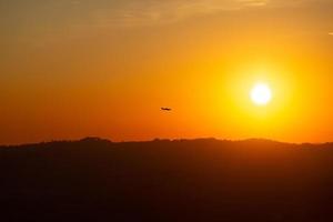 pequeno avião solitário voando ao pôr do sol conceito de lazer e liberdade foto