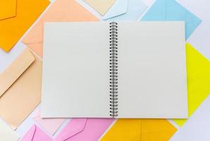 envelopes em tons pastel se alinham em estilo oblíquo com um caderno branco em branco foto