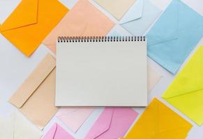 envelopes em tons pastel se alinham em estilo oblíquo com um caderno branco em branco foto