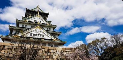 foto da paisagem do castelo de osaka na primavera, onde ainda há algumas flores de cerejeira ainda em flor.